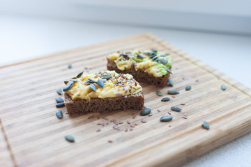 whole grain toast with avocado and flax and pumpkin seeds on a wooden board