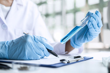 Scientist or medical in lab coat holding test tube with reagent, Laboratory glassware containing chemical liquid, Microscope, Biochemistry laboratory research