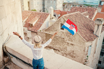 Enjoying vacation in Split. Young traveling woman with national croatian flag enjoying old town...