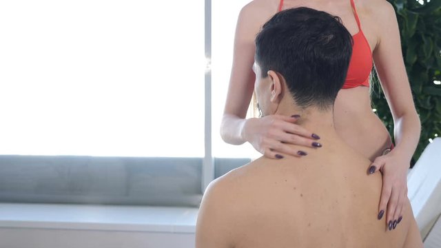 Romantic relationships, passion and wellness concept. Young caucasian couple in spa centre. Back view. Unrecognizable woman touching her man going to kiss. love and dating relationship. close-up shot