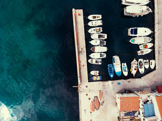 Drone shot of small adriatic harbor and stone pier with fishing boats.
