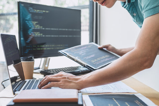 Young Professional programmer working at developing programming and website working in a software develop company office, writing codes and typing data code, Programming with HTML, PHP and javascript