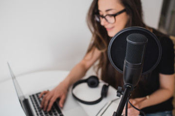 Woman blogger recording radio podcast in studio.