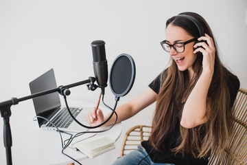 Woman blogger recording radio podcast in studio.