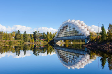 Unique bridge under construction over a still river © Mikael