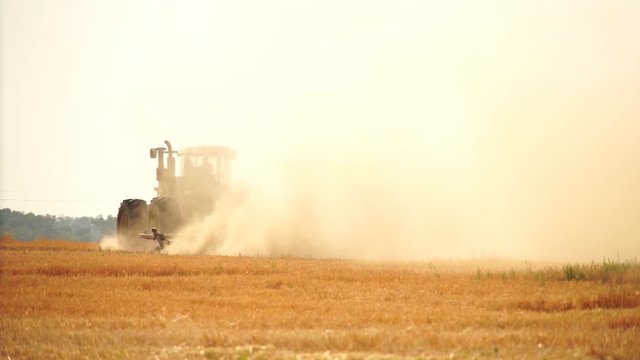 A tractor with a plow plows the field after harvesting. Slow motion	
