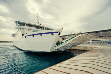 Ferryboat loading or unloading by a port pier. Concept of transportation and traveling.