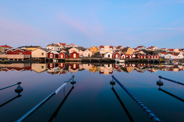 Fototapeta na wymiar Colourful houses reflected in a still harbour, Sweden.