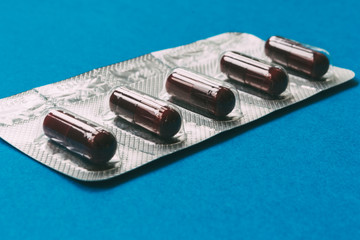blister pack of dark red capsules on a blue background