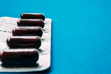 blister pack of dark red capsules on a blue background
