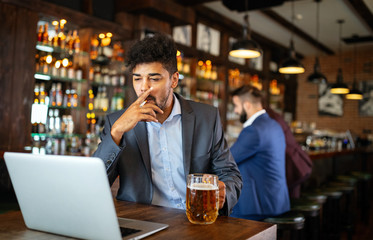 People and bad habits concept. Man drinking beer and smoking cigarette at pub