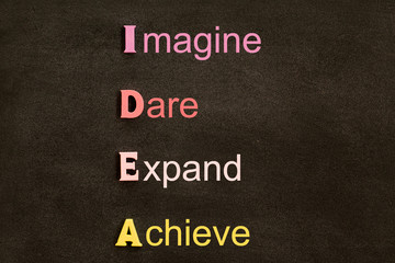 Creative idea acronym, business concept: By arrangement wooden letters (Imagine, Dare, Expand, Achieve) on black chalkboard