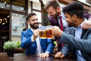 People, men, leisure, friendship and celebration concept. Happy male friends drinking beer at pub