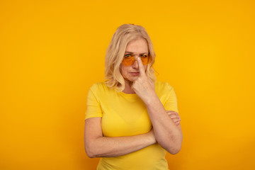 Portrait of serious female in sunglasses in the yellow studio