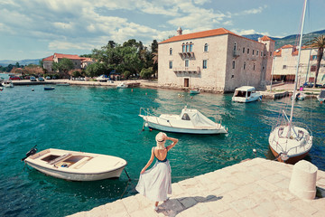Tourism concept. Young traveling woman enjoying the view of Kastel Castle walking near the sea on Croatian coast.