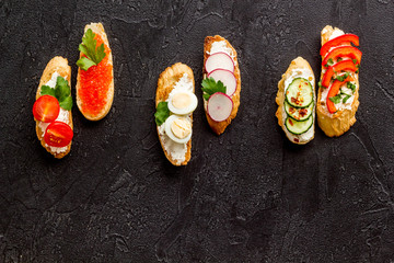 Sandwiches assorti pattern on black background top-down copy space