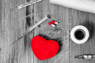 Bandage, pills, syringe and heart on a gray wooden background. Health care. Ambulance. First Aid...