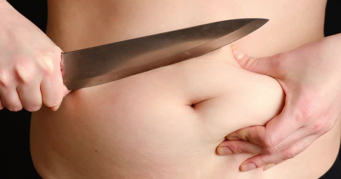 The concept of getting rid of excess weight. Girl cuts off fat deposits with belly knife/