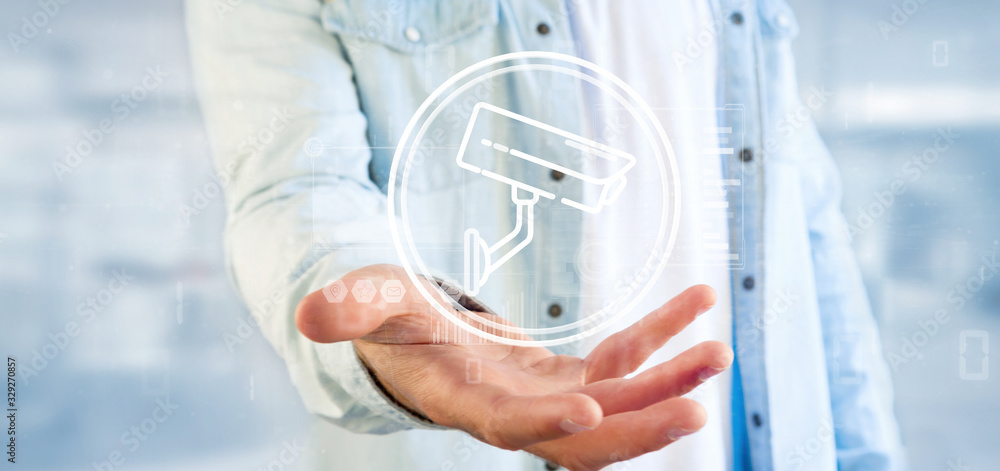 Poster businessman holding security camera system icon and statistics data - 3d rendering