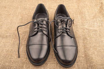 A pair of black leather boots against the rough fabric. Close up.