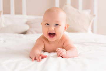 baby boy smiling and lying on a light bed at home