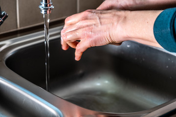 Proper washing of hands demonstrated at steel kitchen sink