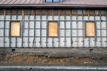 Fototapeta na wymiar covered windows of old wooden building waiting to be demolished