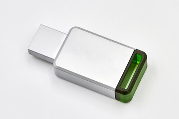 Metal light gray usb stick or flash drive with green plastic element on white background. Data concept. Closeup.