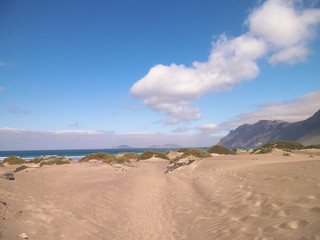 Fototapeta na wymiar Beach and Mountains - beautiful coast in Caleta de Famara, Lanzarote Canary Islands. Beach in Caleta de Famara is very popular among surfers