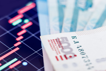 Russian ruble banknotes against backdrop of falling red currencies graphic. Concept economic default, oil