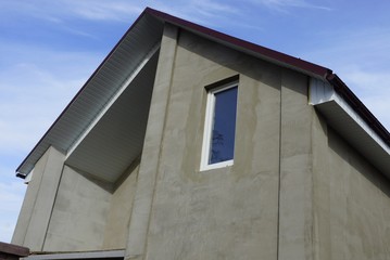 gray concrete loft with one white window against a blue sky on a sunny day