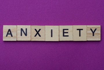 word anxiety from small gray wooden letters lies on a lilac background