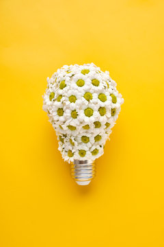 Energy Saving LED Lamp with Flowers over yellow background. Gree