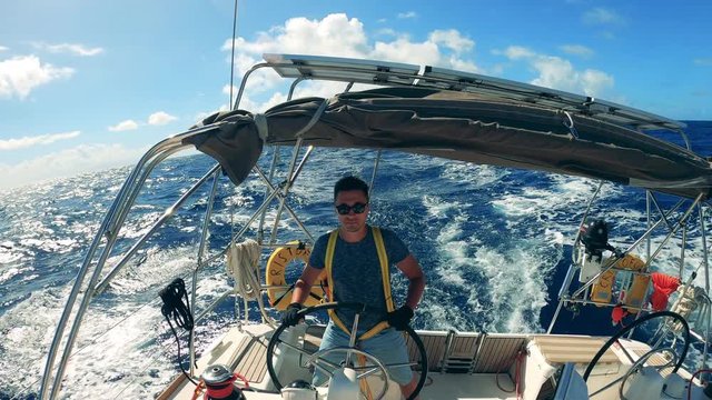 A man is sailing across the sea in his sailboat