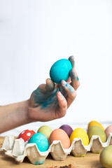 Fototapeta na wymiar Blue Easter egg in woman hand. The process of painting Easter eggs