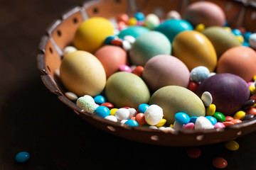 Fototapeta na wymiar Colorful easter eggs and chocolate candies in bowl
