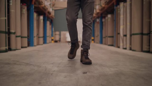 Low section of a manager walking towards camera in the large warehouse distribution center