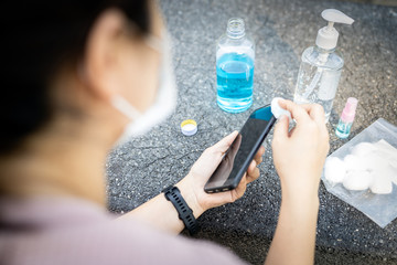 Cleaning mobile phone to eliminate germs,Covid-19.hands of asian woman cleaning the phone by hand...