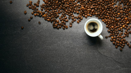 Banner top view of coffee beans and cup on a dark ardesia table