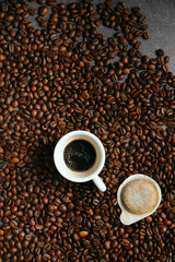 Vertical top view of coffee beans, cup, and cialda  on a dark ardesia table