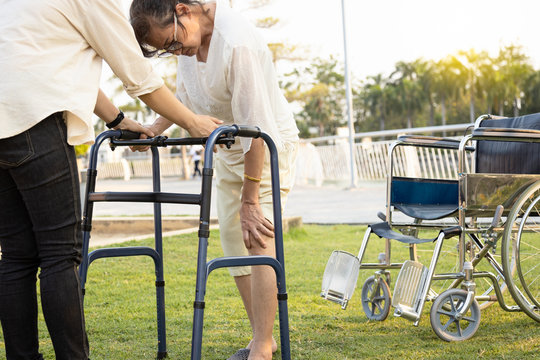 Senior asian female patient hand to touch her knee,have joint hurt,bone problem,painful in the knees while walk use walker during rehabilitation,elderly woman suffer from osteoporosis,gout,rickets