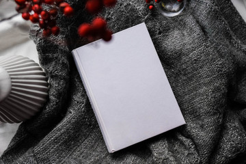 Winter autumn mock up with white book cover. Greetings card new year book mockup with red rowan berries over gray wool plaid. White book cover winter cozy mock-up.Warm festive rowan tree backdrop.