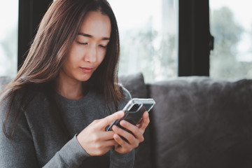 close up short beautiful asian woman using smartphone on the sofa relaxing corner in her house. she is stressed.