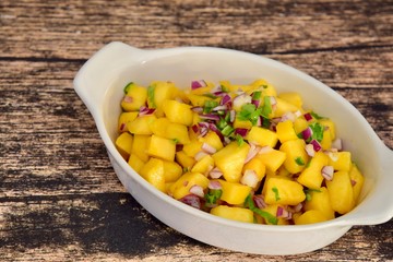Fresh homemade mango salsa in a bowl on wooden background