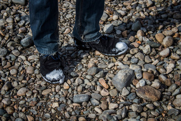 Male legs in blue jeans and winter shoes standing on stones. A blue jeans.