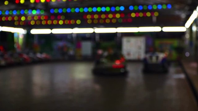 Bumper cars in city amusement park at evening. Blurred video.