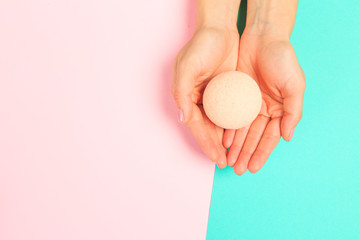 female  manicure. Beautiful young woman's hands holding a bathroom bomb on pastel background .