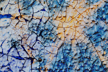 Surface texture with blue and yellow color on a surface structure with thick paint application and with cracks. For abstract backgrounds.