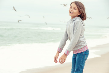 Beautiful girl walks along the beach and seagulls fly around. The concept of freedom, life, enjoyment, solitude and creation.