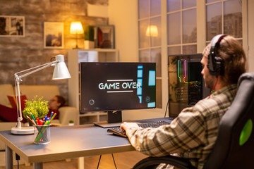 Male gamer losing a video game while playing on his PC late at night in the living room © DC Studio